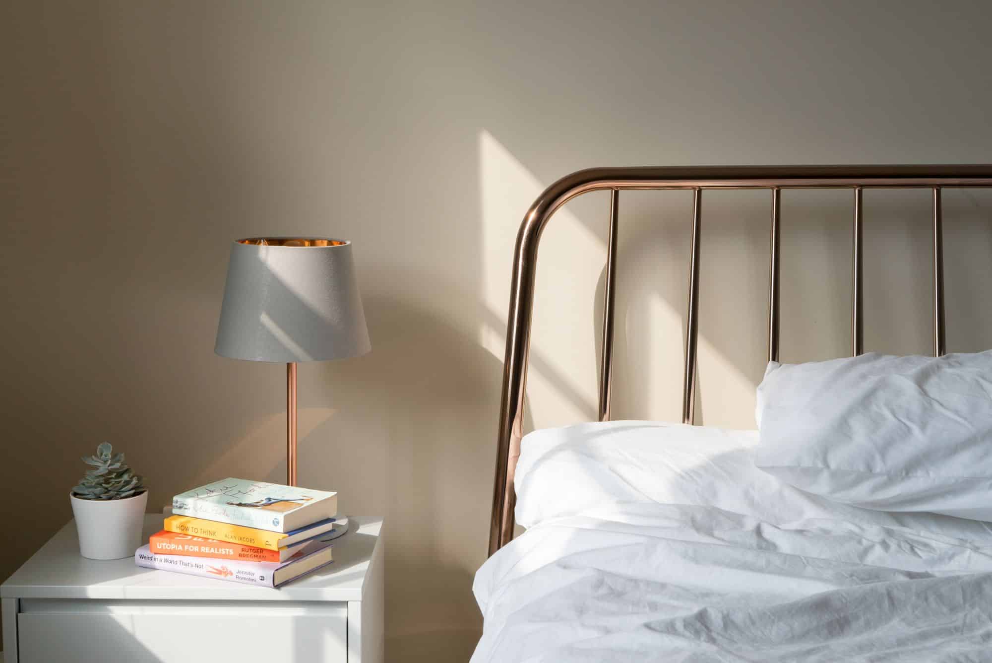 bed with a brass bed frame and a side table