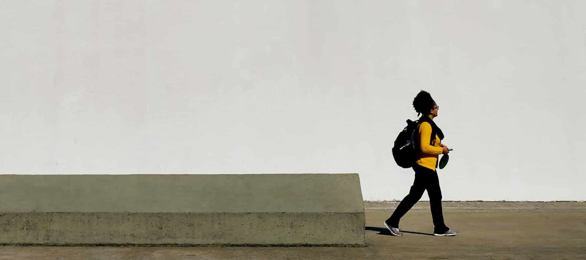 person walking in front of a white wall